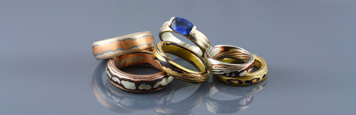 A collection of mokume gane rings featuring 18kt rose gold, 18k yellow gold, 18k white gold, palladium, silver and shakudo. Mokume gane plain rings can be used as wedding bands and mokume gane rings set with gemstones can be beautiful and unique engagement rings.
